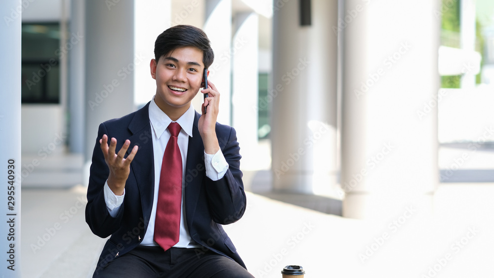 Young businessman in black suit speaking over mobile with partners. Young businessman in black suit speaking over mobile with partners.