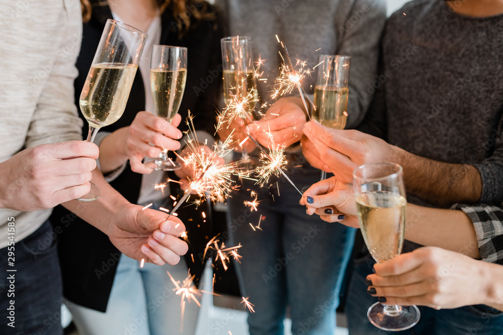 Group of friends holding flutes of sparkling champagne and burning Bengal lights - obrazy, fototapety, plakaty 