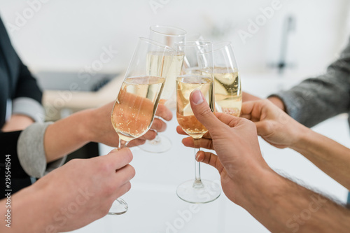 Hands of friends holding flutes of sparkling of champagne and clinking with them