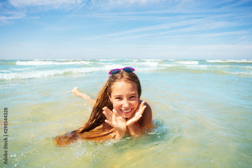 Cute girl play in waves holding palms near face Cute girl play in waves holding palms near face