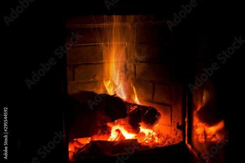 fire burns with wood in a fireplace with blue gas on a black background, holiday of lights, christmas, horizontal