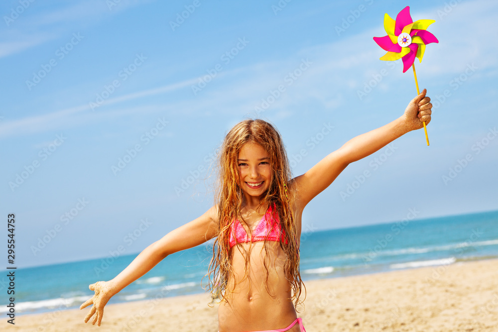 Happy girl smile in bikini on beach with pinwheel - obrazy, fototapety, plakaty 