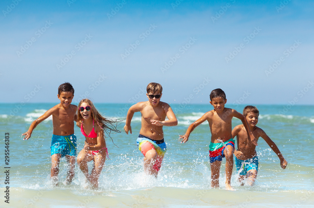 Group of kids running from the sea with splashes Group of kids running from the sea with splashes