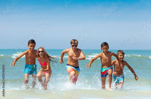 Group of kids running from the sea with splashes