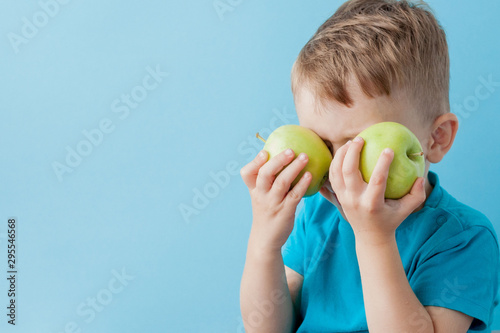 Little Boy Holding an Apples in his hands on blue background, diet and exercise for good health concept