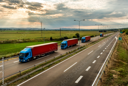 Lorry trucks in line as a caravan or convoy  on country highway under a beautiful sky photo