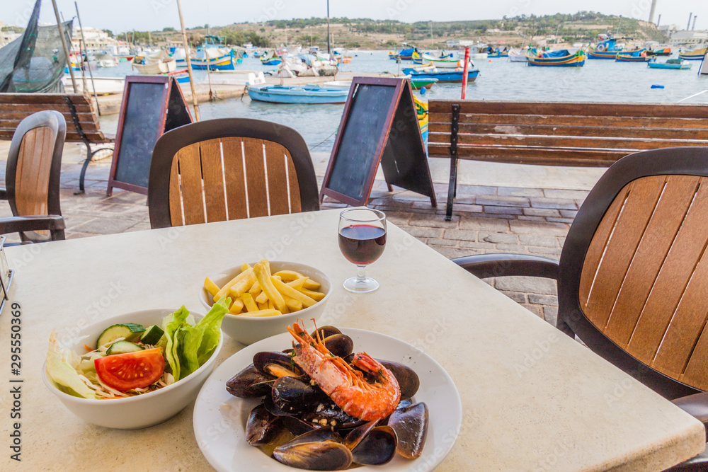Sea food dish with fries and salad in a retaurant in the harbor of Marsaxlokk town, Malta - obrazy, fototapety, plakaty 