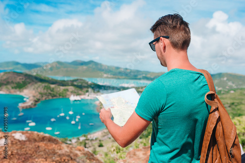 Young tourist man with map background of English Harbor from Shirley Heights, Antigua photo