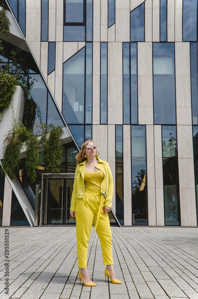A young girl in a yellow suit is having fun dancing in the city center. Handsome and cheerful woman in black glasses. Girl traveling abroad on weekend getaway. A young girl in a yellow suit is having fun dancing in the city center. Handsome and cheerful woman in black glasses. Girl traveling abroad on weekend getaway.