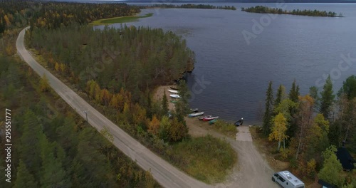 Boats at a lake, Aerial, tilt up, drone shot, over kayaks at the shore of Pallasjarvi, surrounded by fall colored trees, on a sunny, autumn day, in Pallas-Yllas national park, Muonio, Lapland, Finland photo