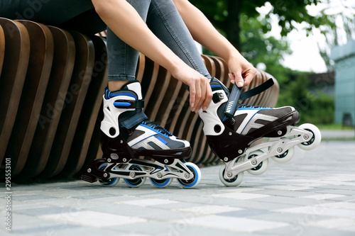 Woman wearing modern inline roller skates in city park  closeup