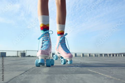 Young woman with vintage roller skates in city on sunny day, closeup view photo