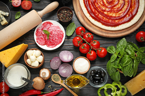 Quadro su tela Flat lay composition with pizza crust and ingredients on dark wooden table