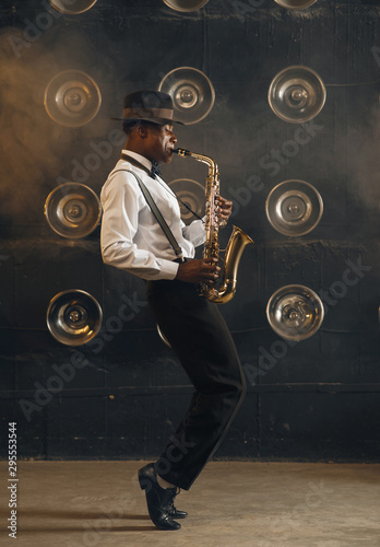 Konstfotografi Black jazzman in hat plays the saxophone on stage