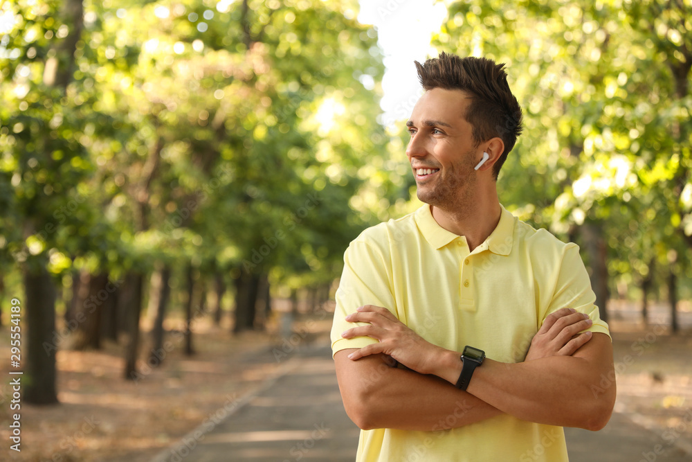Young man with wireless earphones in park Young man with wireless earphones in park