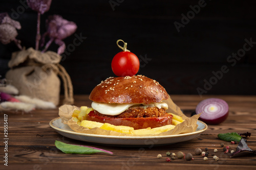 Foto cheeseburger decorated with cherry tomato on a plate on a wooden table