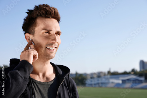 Young sportsman with wireless earphones at stadium