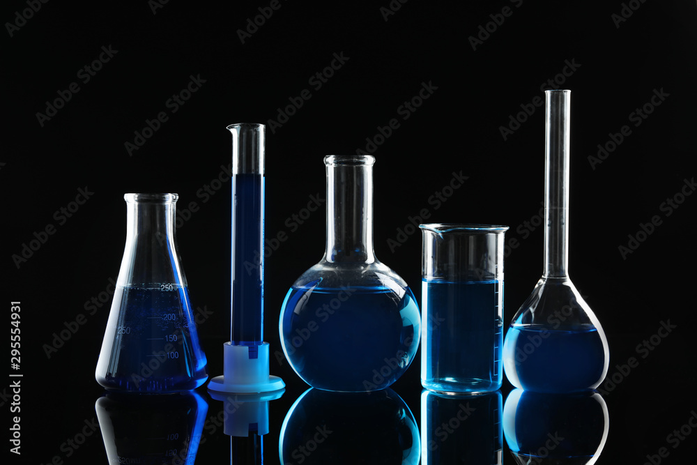 Laboratory glassware with blue liquids on black background Laboratory glassware with blue liquids on black background