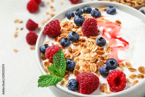 Tasty homemade granola with yogurt and berries on light table, closeup. Healthy breakfast