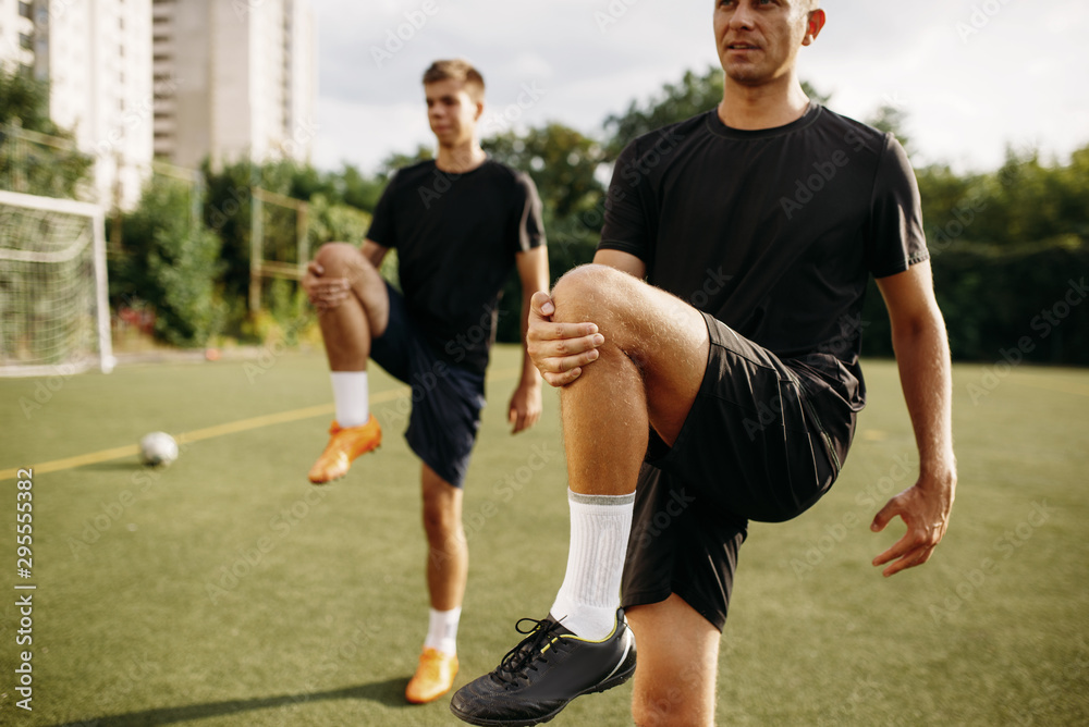 Obraz premium Male soccer players doing stretching exercise