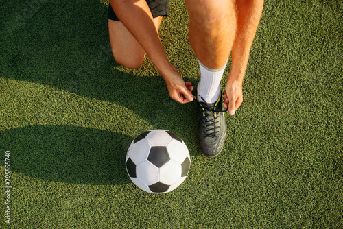 Fototapeta Naklejka Na Ścianę i Meble -  Male soccer player ties his shoelaces on boots