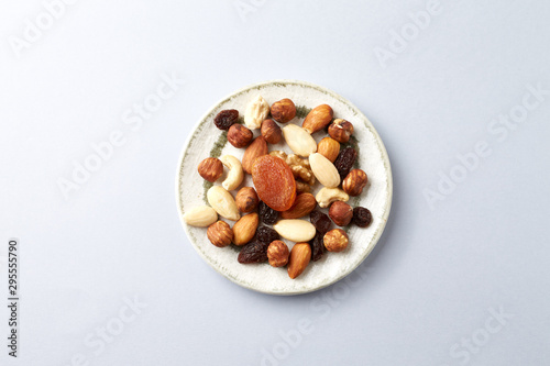 Nuts, raisins and apricots on bright paper background. Concept for healthy snack. Top view. Copy space. 