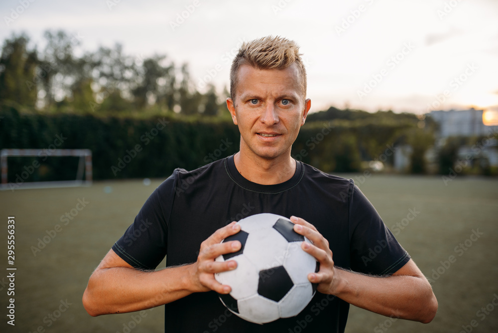 Soccer player holding ball in hands on the field