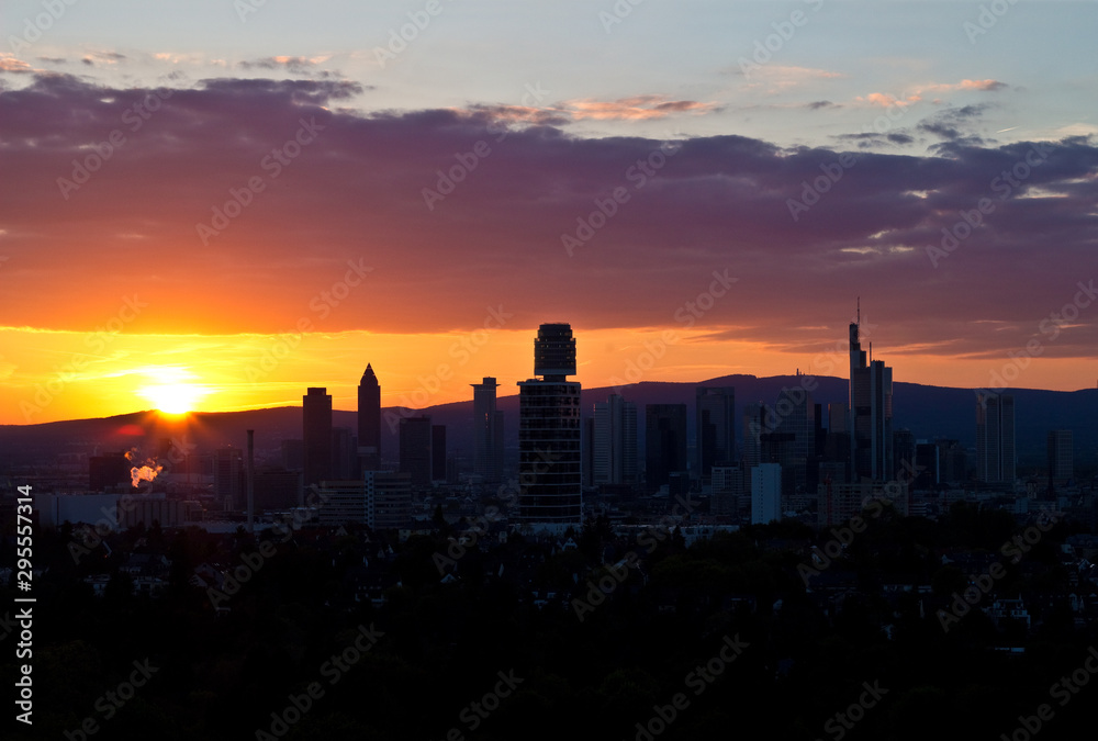 Blick auf die Skyline der Finanzmetropole Frankfurt am Main im Gegenlicht eines Sonnenuntergangs des im Hintergrund liegenden Mittelgebirge.