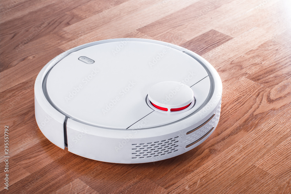 white robotic vacuum cleaner in rays of morning sun. robot controlled by voice commands for direct cleaning. modern smart appliance for cleaning house white robotic vacuum cleaner in rays of morning sun. robot controlled by voice commands for direct cleaning. modern smart appliance for cleaning house