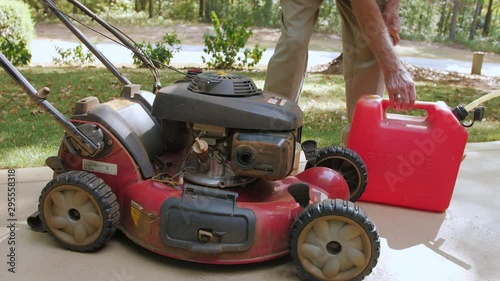 Male landscaper fueling gas powered push lawn mower.