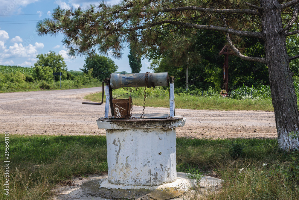 Old weel with rusty bucket next to country road in Moldova
