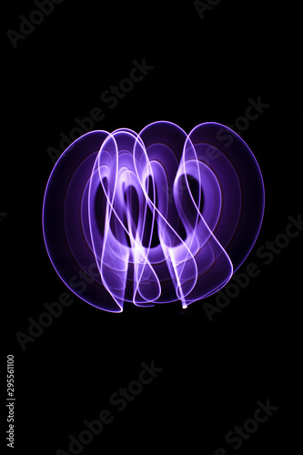 Curved abstract shapes made of violet light saber in background. Lightpainting session in long exposure at night.