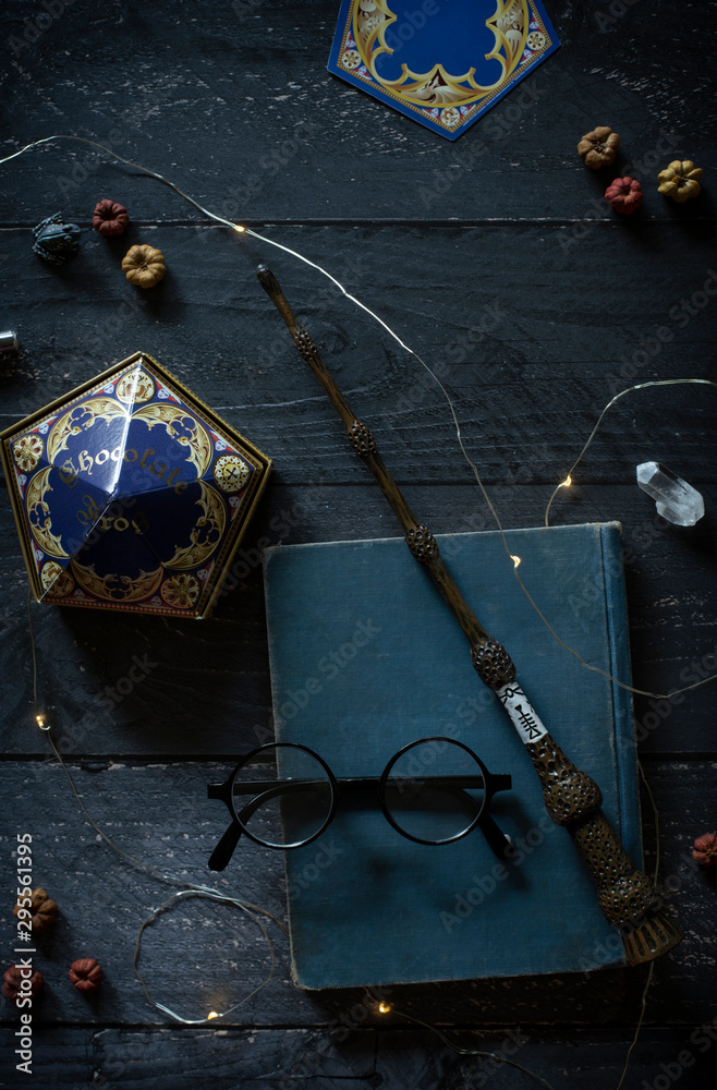 Fototapeta premium magic wand and spell books on desk with glasses and other witch items, wizards desk, halloween theme, vintage books