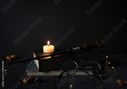 Fotografia, Obraz magic wand and spell books on desk with glasses, burning candle, and other witch
