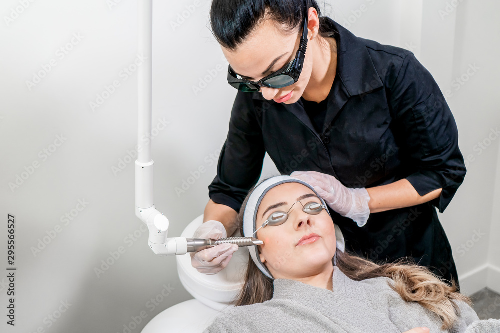 Beauty laser technician performing a cosmetic skin resurfacing session on a  female patient, also called a laser peel or photofacial, with an Er:Yag  laser (infrared wavelength). foto de Stock | Adobe Stock