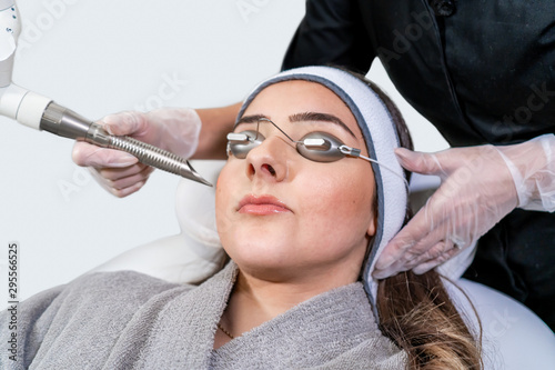 Beauty laser technician performing a cosmetic skin resurfacing session on a female patient, also called a laser peel  or photofacial, with an Er:Yag laser (infrared wavelength). photo