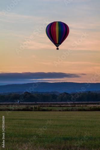 Rainbow hot-air balloon floats over field at sunrise, portrait © rabbitti