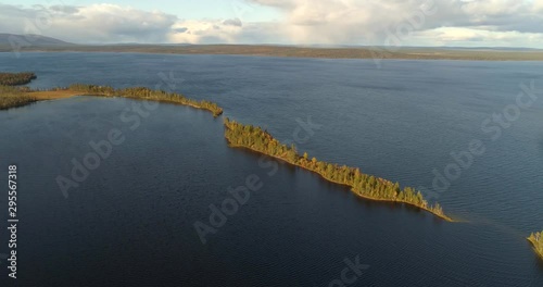 Islands on a lapland lake, Aerial, tracking, drone shot, around a ester, full of autum color trees, at a pallasjarvi, revealing Ounastunturit fells, on a sunny, fall day, in Pallas-Yllas, Finland photo