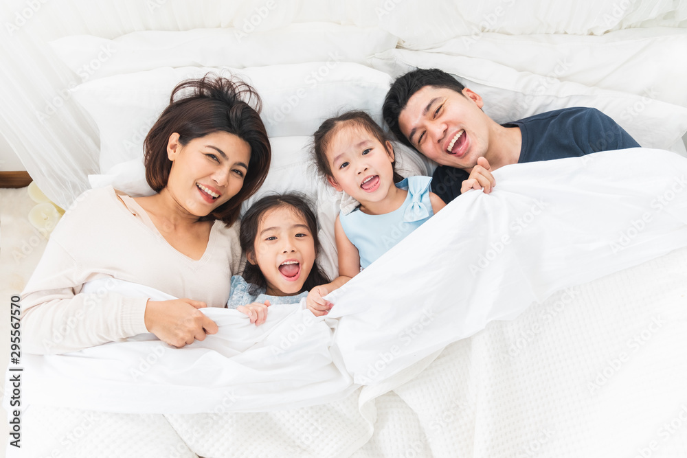 Happy Asian family laying on bed in bedroom with happy and smile, top view Happy Asian family laying on bed in bedroom with happy and smile, top view