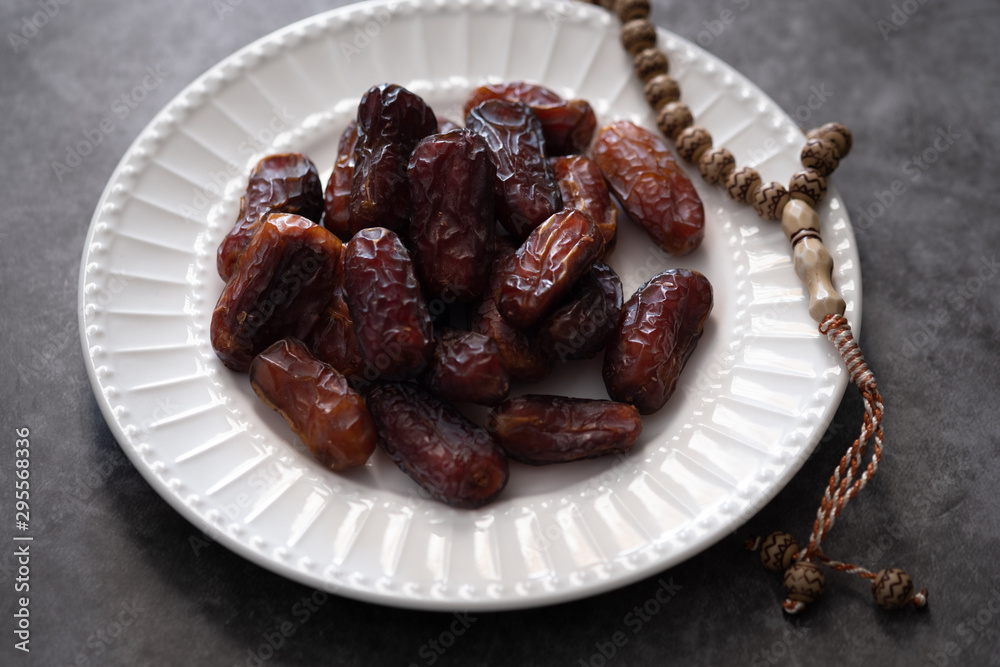 Dates, rosary on white ceramic plate. Ramadan concept. Dates, rosary on white ceramic plate. Ramadan concept.