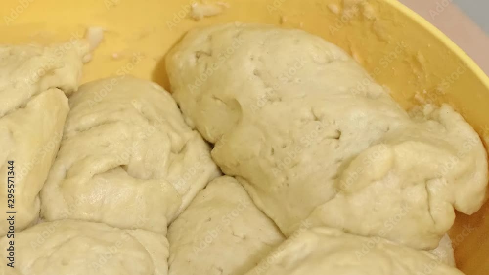 Woman grabbing piece of raw dough from bowl full of dough; making dinner rolls; slow motion. Woman grabbing piece of raw dough from bowl full of dough; making dinner rolls; slow motion.