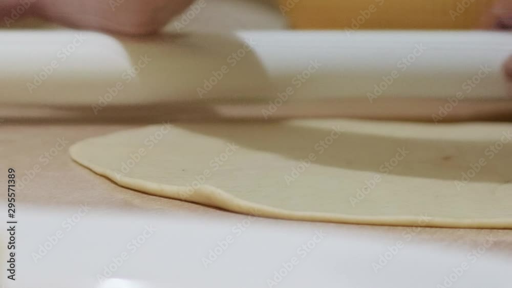 Woman using rolling pin to roll out dough for fresh dinner rolls; ingredients; slow motion. Woman using rolling pin to roll out dough for fresh dinner rolls; ingredients; slow motion.