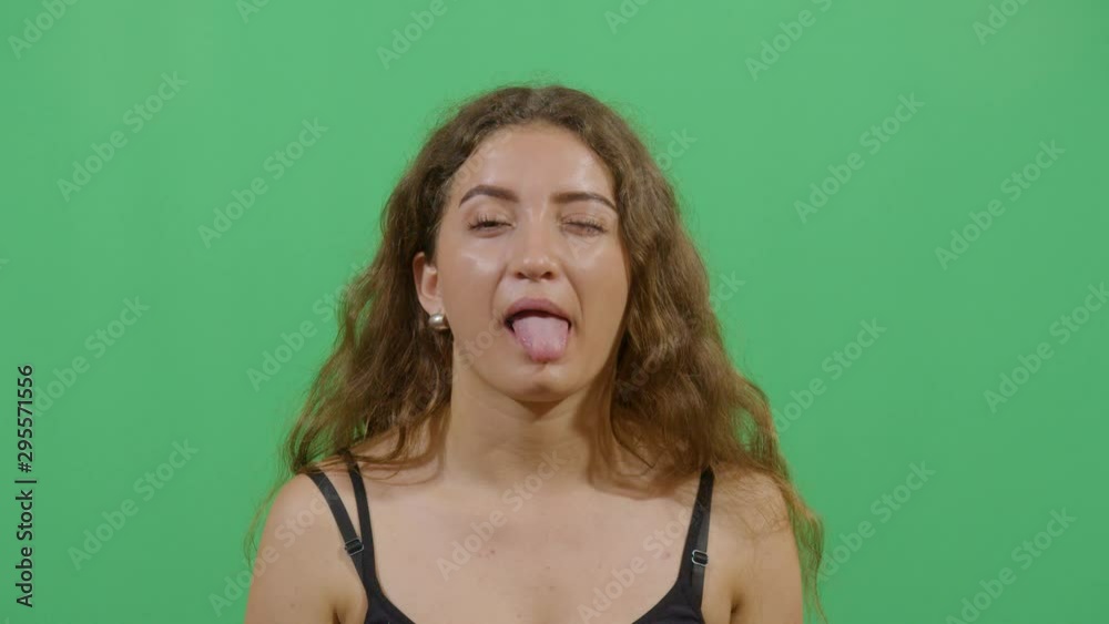 Tongue Sticking And Winking By A Woman Starting From A Calm State And Going Unpredictable. Studio Isolated Shot Against Green Screen Background Tongue Sticking And Winking By A Woman Starting From A Calm State And Going Unpredictable. Studio Isolated Shot Against Green Screen Background