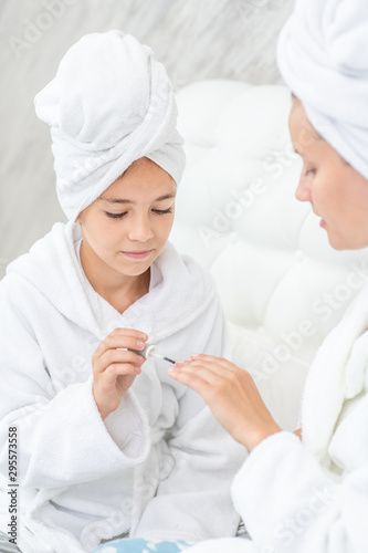 Young girl manicures her smilng mother at home