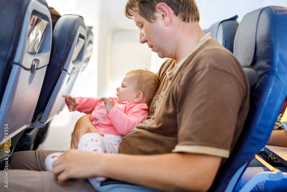 Young tired father and his crying baby daughter during flight on airplane going on vacations Young tired father and his crying baby daughter during flight on airplane going on vacations