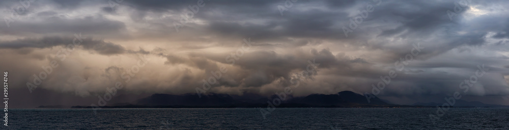 Dramatic Panoramic View of a cloudscape during a dark, rainy and colorful sunset. Taken on the Ocean Coast of Alaska, USA. - obrazy, fototapety, plakaty 