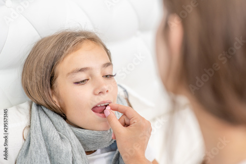 Mother giving pill to her sick daughter at home