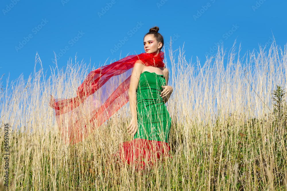 Obraz premium Young beautiful girl model paziruet on the green grass, summer freedom and enjoy the concept.