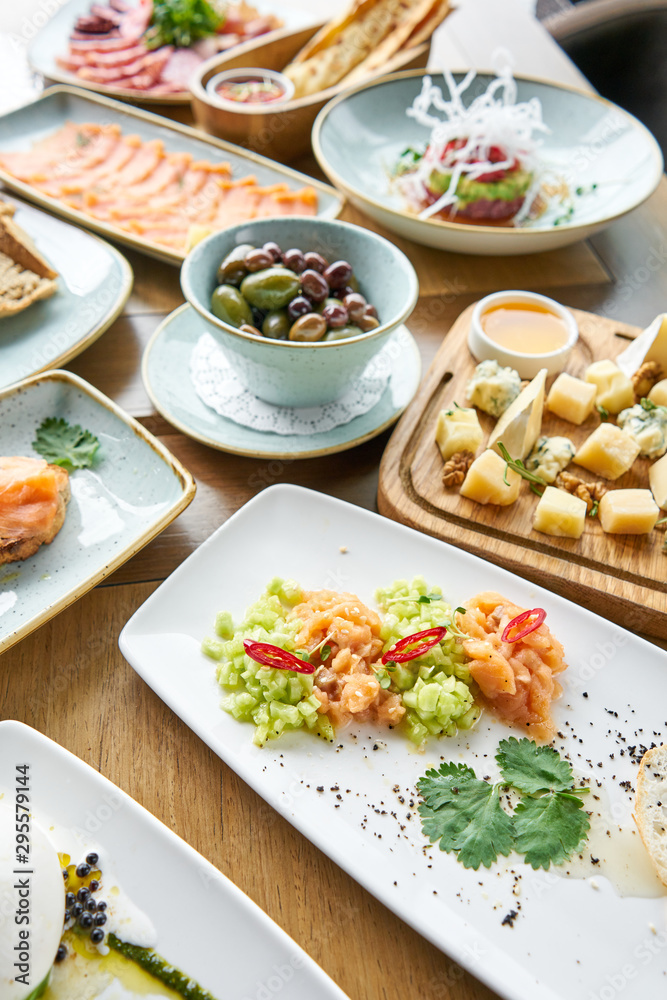 Salmon tartare in the restaurant. Variety of dishes on the table. Various snacks and antipasti on the table. Restaurant menu. Italian cuisine
