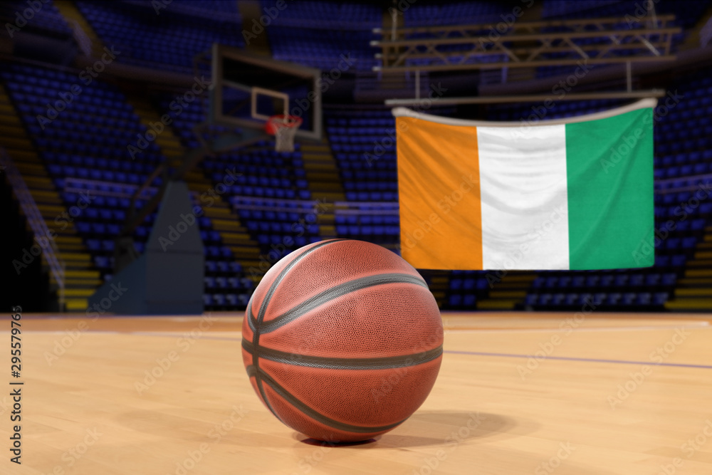 Naklejka premium Ivory Coast flag and basketball on Court Floor